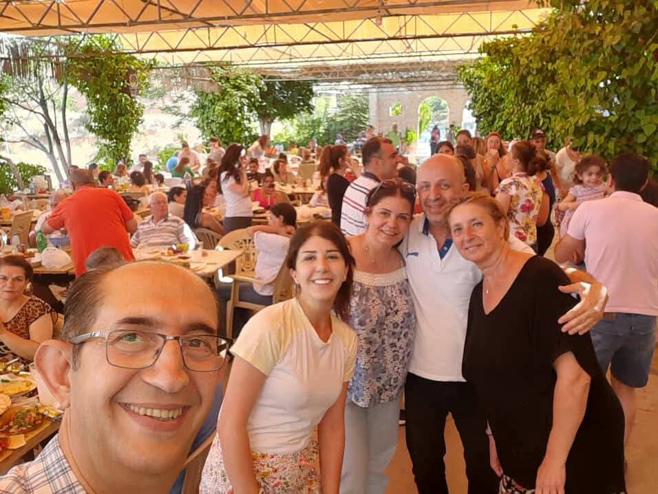 Smiling members of the community together at an outdoor gathering with families seated at tables