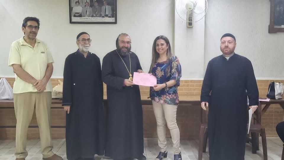 A graduate receiving a certificate from clergy, with association members standing alongside