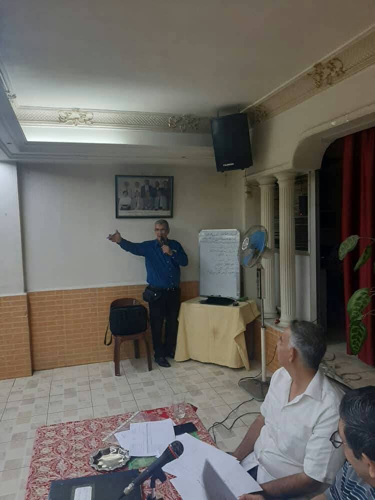 A man with a microphone presenting beside a flipchart in the association hall
