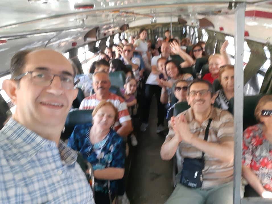 A bus filled with smiling members of the community during an association outing