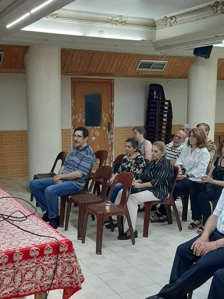 Members seated on chairs following a meeting in the association hall