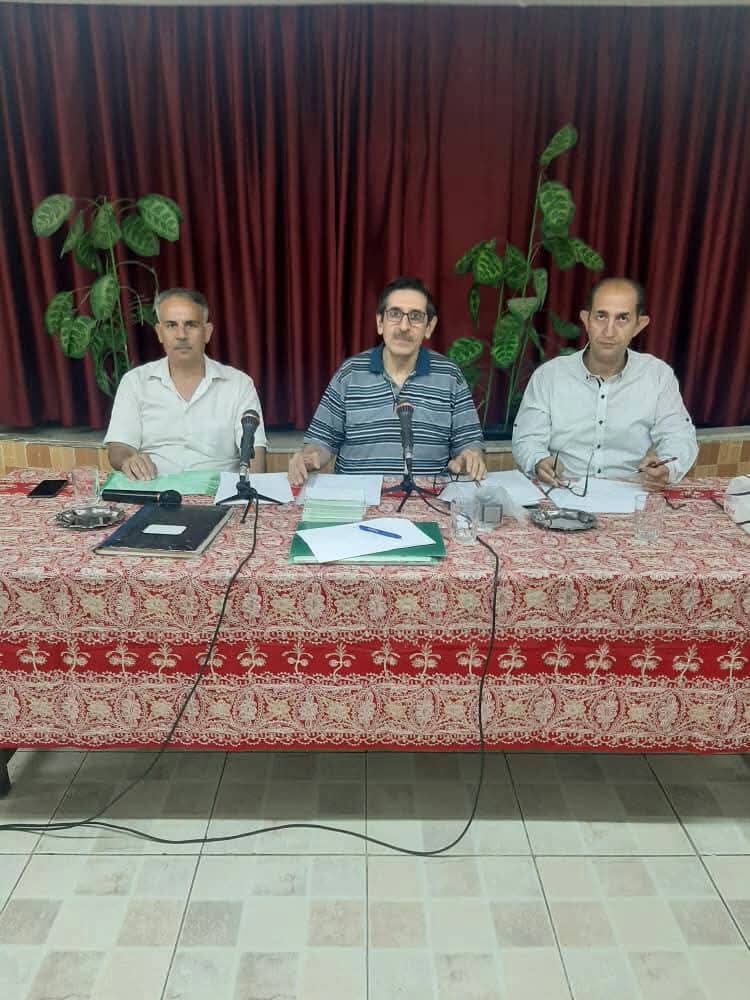 Three association officers seated behind microphones at the head table of a general meeting