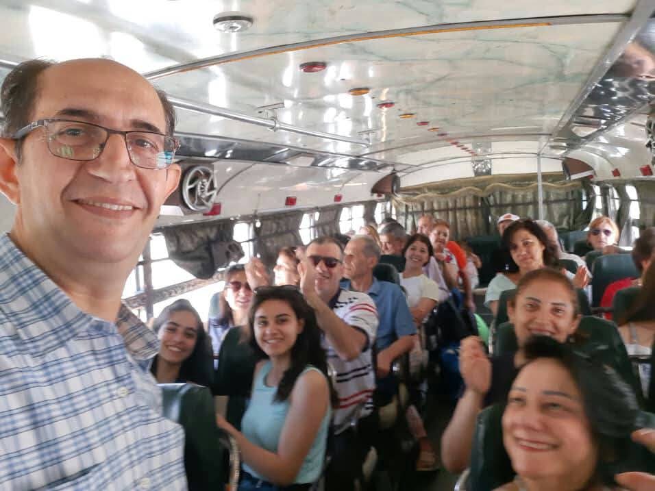 Smiling participants of all ages seated inside a coach during an association trip